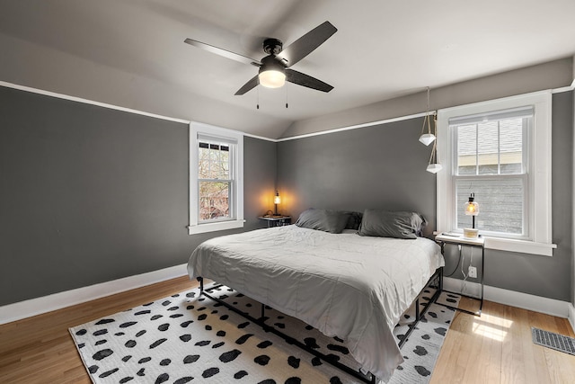 bedroom featuring a ceiling fan, baseboards, visible vents, and wood finished floors