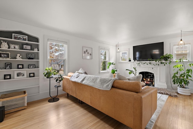 living area with plenty of natural light, built in features, hardwood / wood-style flooring, and a fireplace