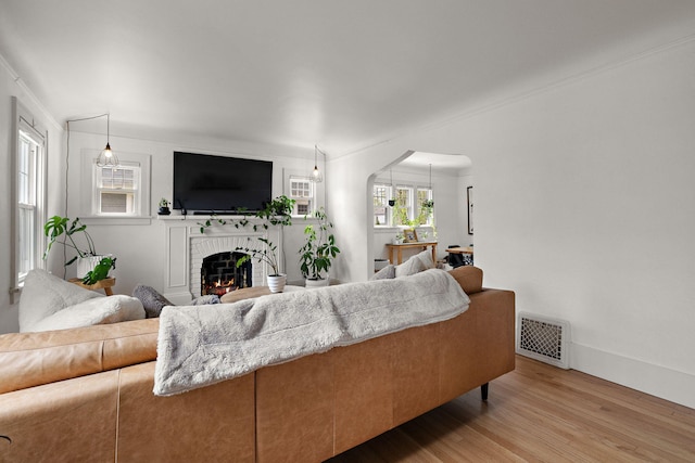 living room with arched walkways, visible vents, wood finished floors, and a fireplace