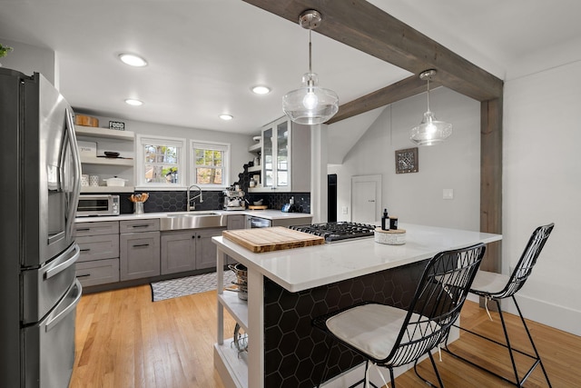kitchen featuring backsplash, open shelves, gray cabinetry, a sink, and stainless steel appliances