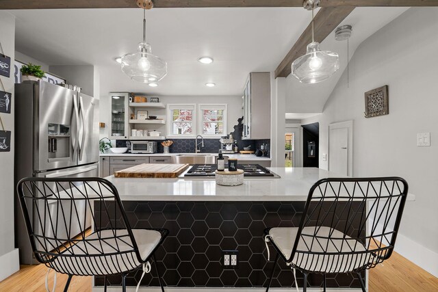 kitchen featuring light wood-style floors, a sink, appliances with stainless steel finishes, and a kitchen bar