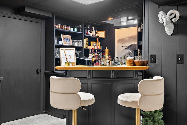 bar featuring a bar, a paneled ceiling, and carpet floors