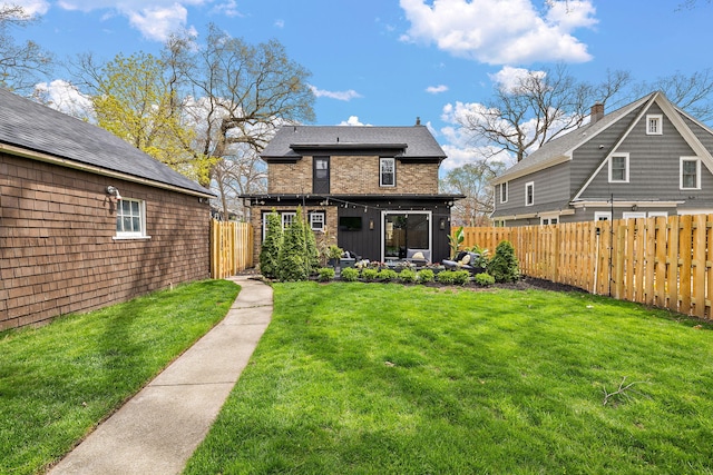 back of property with a fenced backyard and a yard