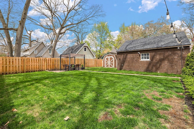 view of yard with an outbuilding, a fenced backyard, and a storage unit