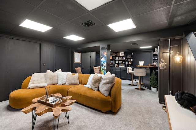 carpeted living room with visible vents and a drop ceiling