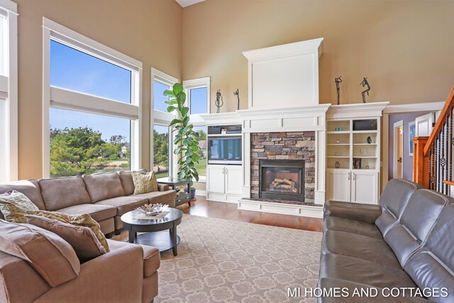 9145 Winterberry Dr, West Olive, MI 49460 - living room featuring a towering ceiling, wood finished floors, a stone fireplace, and stairway
