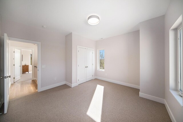 205 Sunset Rd, Ann Arbor, MI 48103 - unfurnished bedroom with baseboards, a closet, and light colored carpet
