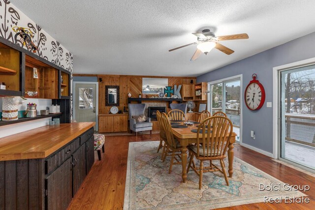 4600 S Teal Ln, Newaygo, MI 49337 - dining area featuring wood walls, dark wood-style flooring, baseboards, a textured ceiling, and a ceiling fan
