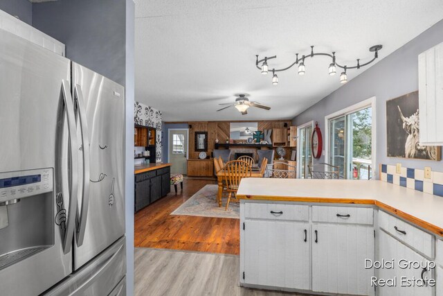 4600 S Teal Ln, Newaygo, MI 49337 - kitchen featuring a peninsula, stainless steel refrigerator with ice dispenser, light countertops, white cabinets, and light wood finished floors