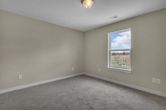 spare room featuring baseboards, visible vents, and carpet