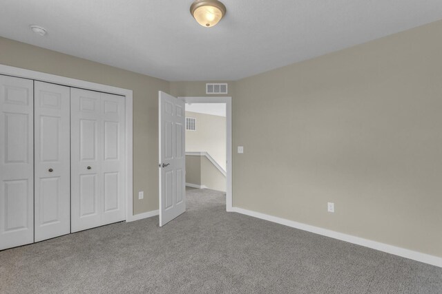 unfurnished bedroom with carpet flooring, baseboards, visible vents, and a closet