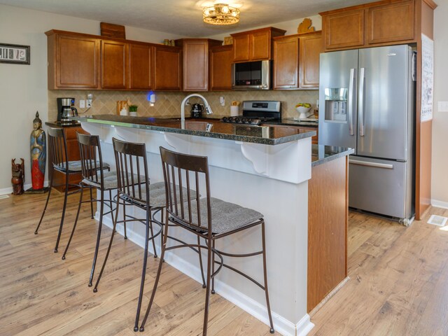 30777 Packard St, Paw Paw, MI 49079 - kitchen featuring appliances with stainless steel finishes, light wood-style floors, brown cabinets, and decorative backsplash