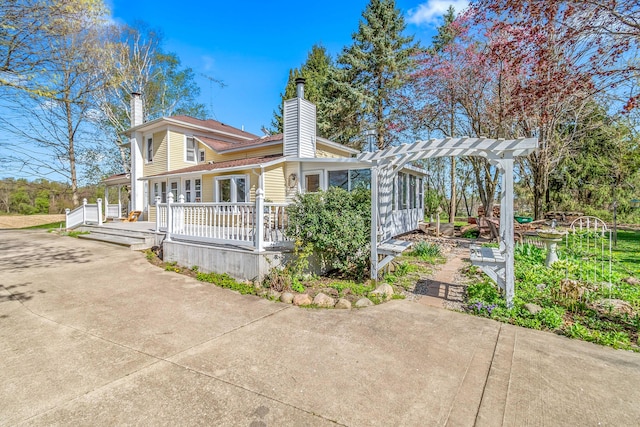 exterior space with a porch, a pergola, and a chimney