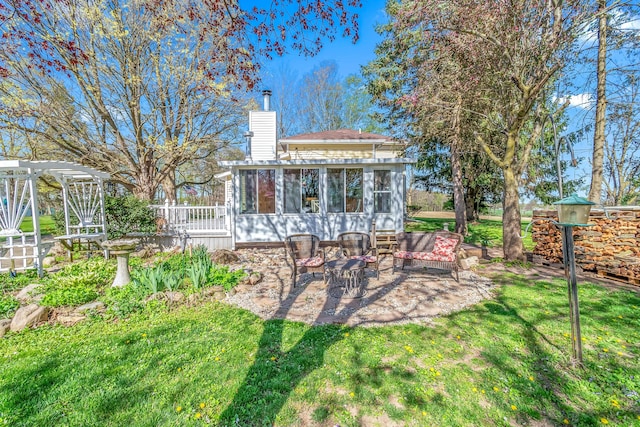 rear view of property with outdoor lounge area, a patio, a chimney, a sunroom, and a lawn