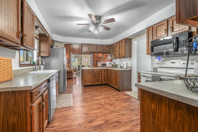 kitchen featuring dark wood-style flooring, a peninsula, black microwave, a ceiling fan, and dishwasher