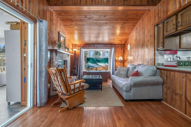 living area featuring a wealth of natural light, light wood-style flooring, wooden walls, and vaulted ceiling