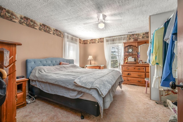 bedroom with ceiling fan, carpet floors, multiple windows, and a textured ceiling