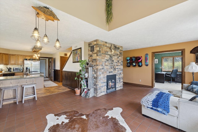 tiled living room with a stone fireplace, a textured ceiling, a toaster, and a notable chandelier
