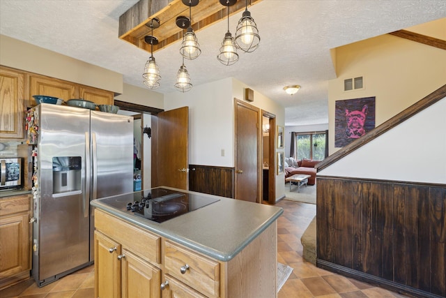 kitchen with dark countertops, appliances with stainless steel finishes, a textured ceiling, a kitchen island, and visible vents