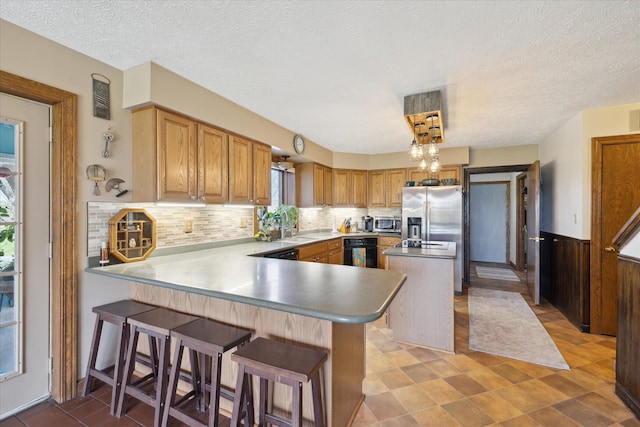 kitchen with a textured ceiling, a peninsula, decorative backsplash, a kitchen island, and black appliances
