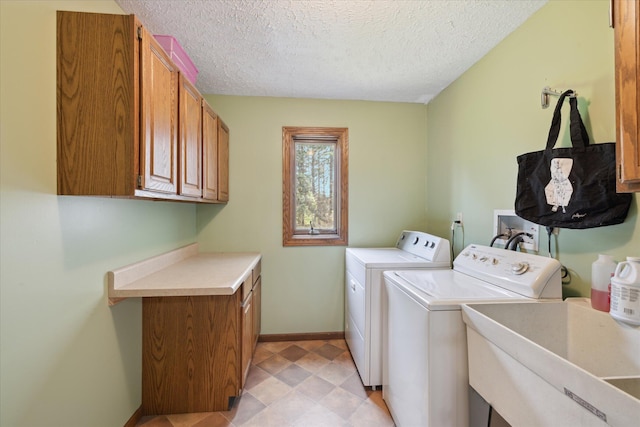 washroom featuring baseboards, a textured ceiling, washing machine and clothes dryer, a sink, and cabinet space