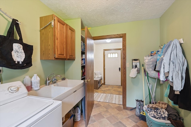 clothes washing area featuring a textured ceiling, baseboards, cabinet space, and washer / clothes dryer