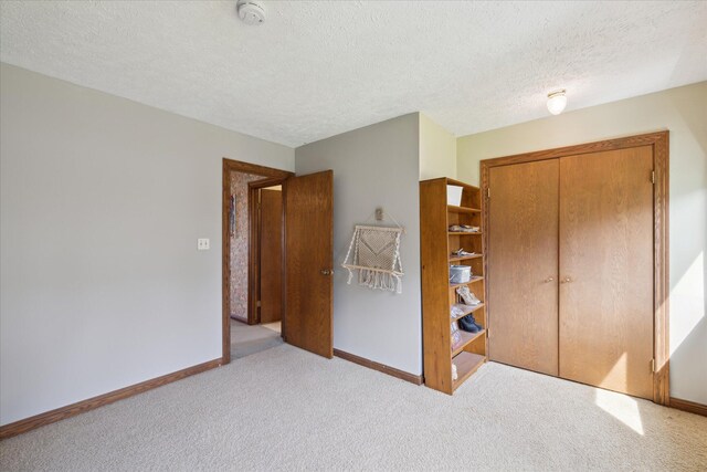 unfurnished bedroom with baseboards, carpet flooring, and a closet