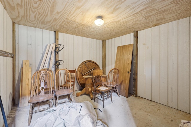 living area featuring wood walls and concrete floors