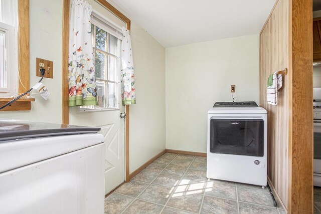 clothes washing area featuring baseboards, laundry area, and washer and clothes dryer
