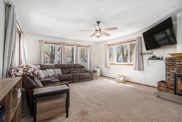 carpeted living room featuring baseboards, a ceiling fan, a wealth of natural light, and a fireplace