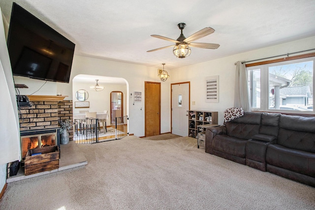 carpeted living room featuring arched walkways and a ceiling fan