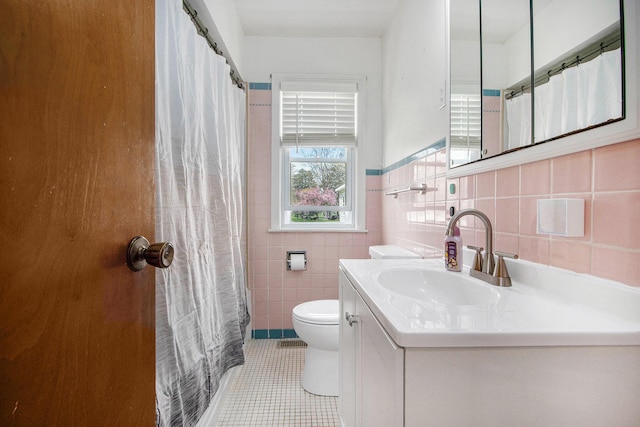full bath featuring tile walls, vanity, a wainscoted wall, tile patterned floors, and toilet