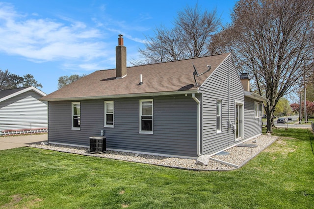 rear view of property featuring a lawn, central AC unit, and a chimney