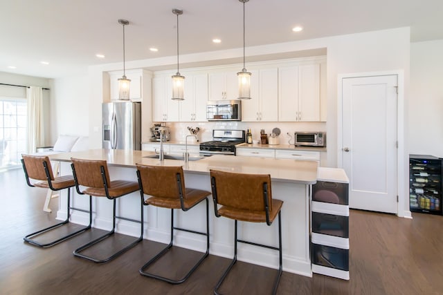 2841 Hardwick Rd, Ann Arbor, MI 48105 - kitchen featuring a center island with sink, white cabinets, a sink, backsplash, and stainless steel appliances