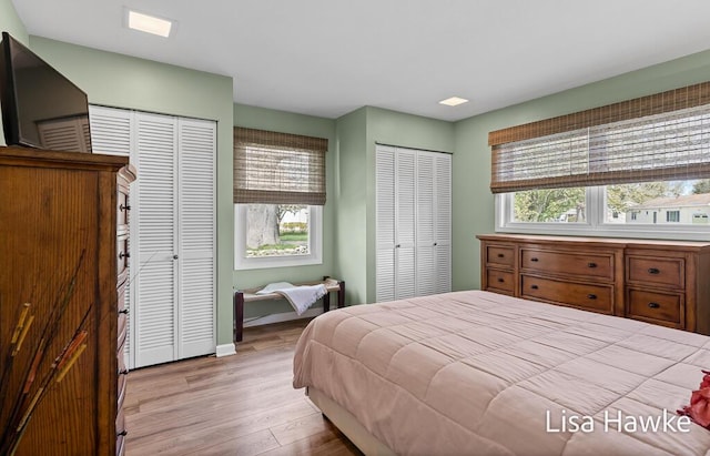 bedroom with light wood-style floors, baseboards, and two closets