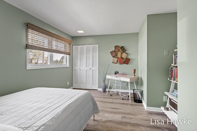 bedroom with baseboards, wood finished floors, and a closet