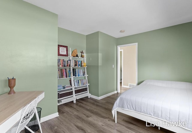 bedroom featuring baseboards, wood finished floors, and visible vents