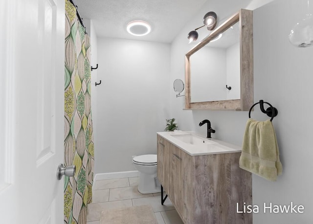 bathroom with vanity, tile patterned flooring, toilet, baseboards, and a textured ceiling
