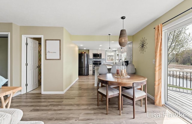 dining room with recessed lighting, baseboards, a fireplace, and light wood finished floors
