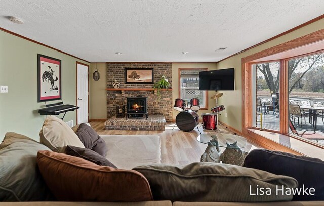 living area with a textured ceiling, ornamental molding, baseboards, and wood finished floors