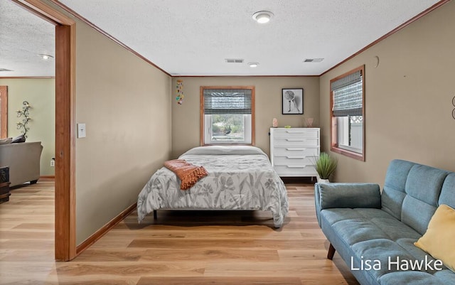 bedroom featuring crown molding, light wood-style floors, and a textured ceiling