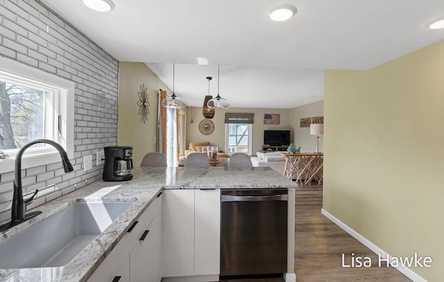 kitchen featuring stainless steel dishwasher, a sink, white cabinets, a peninsula, and dark wood-type flooring
