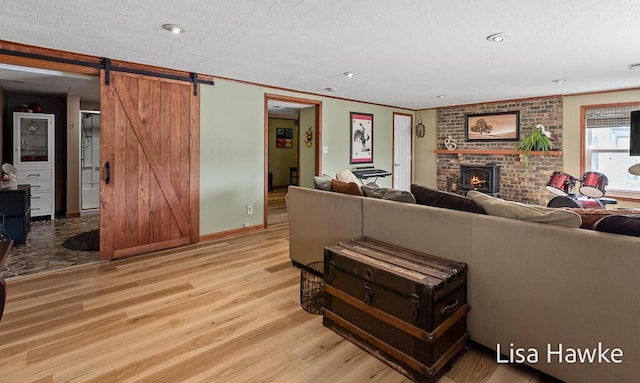living area with a barn door, a brick fireplace, recessed lighting, wood finished floors, and ornamental molding