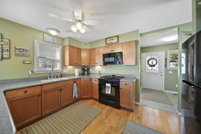 5576 Rays Dr, Onsted, MI 49265 - kitchen with brown cabinets, a sink, light wood-style floors, a ceiling fan, and black appliances