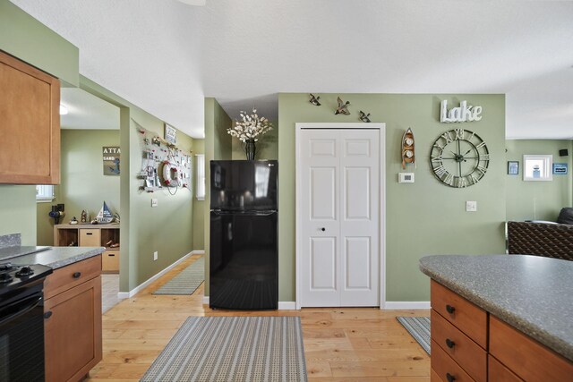 5576 Rays Dr, Onsted, MI 49265 - kitchen featuring brown cabinetry, light wood finished floors, black appliances, and dark countertops