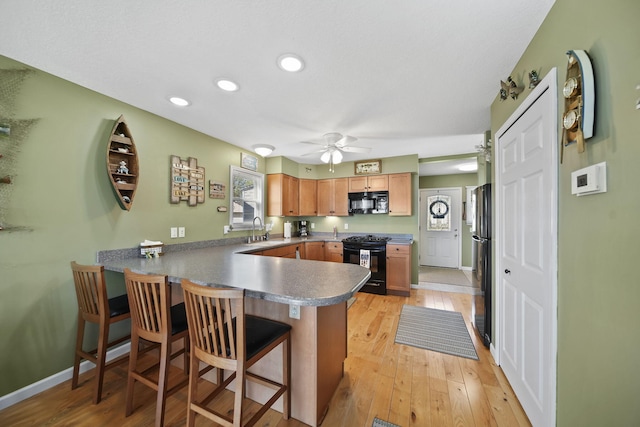 5576 Rays Dr, Onsted, MI 49265 - kitchen with ceiling fan, a sink, a breakfast bar area, a peninsula, and black appliances