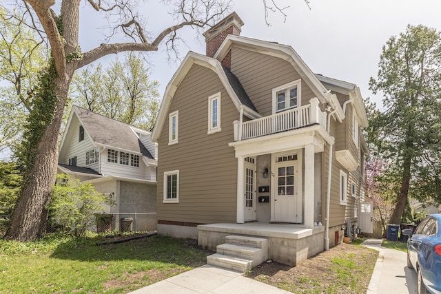 1324 Wells St, Ann Arbor, MI 48104 - view of front of home featuring a front lawn, a chimney, a balcony, and a gambrel roof