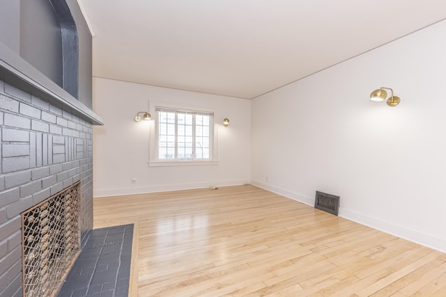 1324 Wells St, Ann Arbor, MI 48104 - unfurnished living room with visible vents, a brick fireplace, and wood finished floors