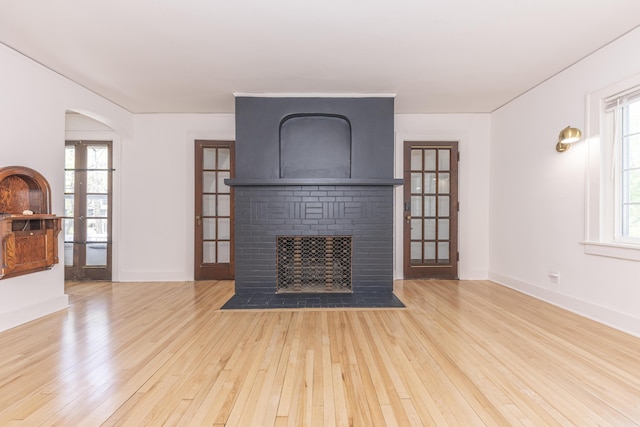 1324 Wells St, Ann Arbor, MI 48104 - unfurnished living room with a healthy amount of sunlight, a fireplace, french doors, and hardwood / wood-style flooring