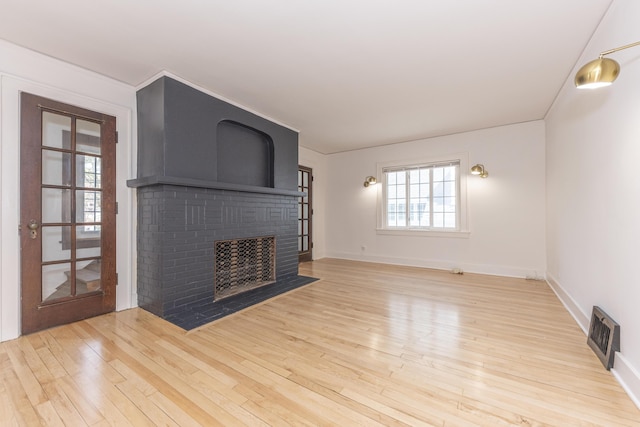 1324 Wells St, Ann Arbor, MI 48104 - unfurnished living room featuring baseboards, wood finished floors, visible vents, and a fireplace